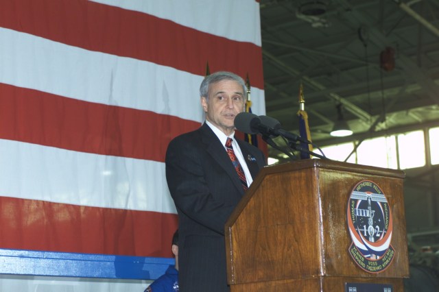 JSC Acting Director Roy S. Estess introduces the STS-102 and Expedition One crew members (out of frame) to a crowd gathered in Ellington Field's Hangar 990 during crew return ceremonies.