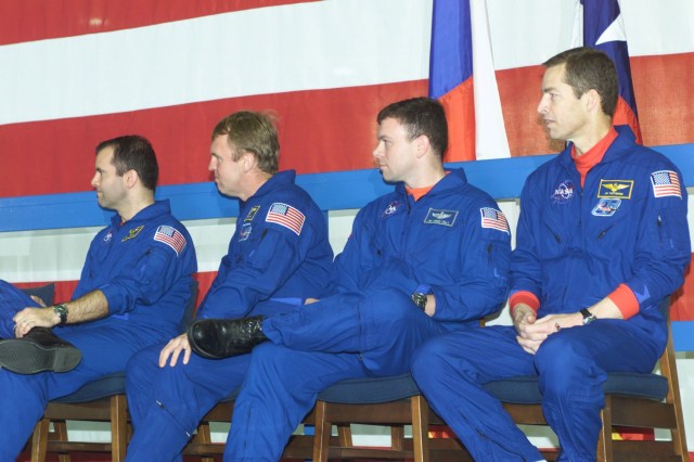 Four STS-102 crew members direct their attention to a lectern (out of frame) in Ellington Field's Hangar 990 where a member of ISS Expedition One addresses a crowd on hand for a welcoming ceremony for the two crews. From the left are astronauts Paul W. Richards and Andrew S.W. Thomas, both mission specialists; along with astronauts James M. Kelly and James D. Wetherbee, pilot and commander, respectively.