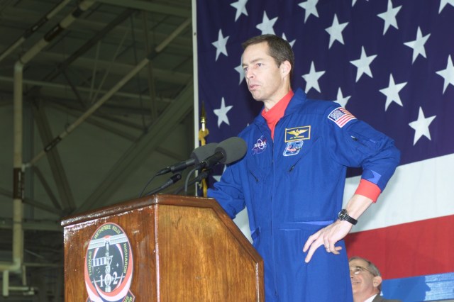 Astronaut James D. Wetherbee, STS-102 commander, addresses a crowd gathered at Ellington Field's Hangar 990 for a crew return ceremony. At lower right is Joseph Rothenberg, NASA Associate Administrator for Space Flight.