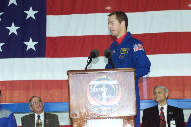 Astronaut James D. Wetherbee, STS-102 mission commander, speaks to a crowd of greeters during a crew return ceremony in Ellington Field's Hangar 990. Pictured in the background on the dais are Joseph Rothenberg (left), NASA Associate Administrator for Space Flight, and Roy S. Estess, Johnson Space Center's Acting Director.