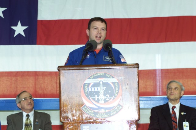 Astronaut James M. Kelly, STS-102 pilot, speaks to a crowd of greeters during a crew return ceremony in Ellington Field's Hangar 990. Pictured in the background on the dais are Joseph Rothenberg (left), NASA Associate Administrator for Space Flight, and Roy S. Estess, Johnson Space Center Acting Director.