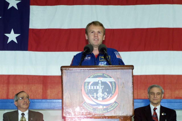 Astronaut Andrew S.W. Thomas, STS-102 mission specialist, speaks to a crowd of greeters during a crew return ceremony in Hangar 990 at Ellington Field. In the background are Joseph Rothenberg (left), NASA Associate Administrator for Space Flight, and Roy S. Estess, Acting Director of the Johnson Space Center (JSC).