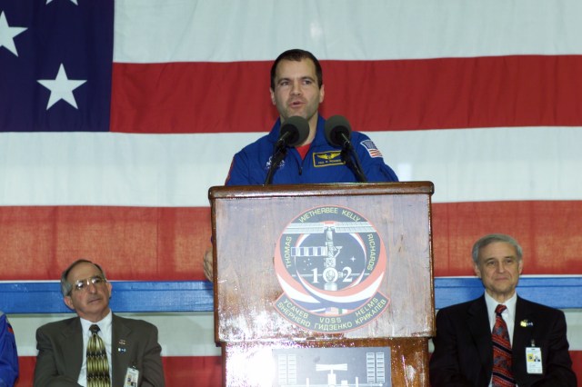 Astronaut Paul W. Richards, STS-102 mission specialist, speaks to a crowd of greeters during a crew return ceremony in Ellington Field's Hangar 990. Pictured in the background on the dais are Joseph Rothenberg (left), NASA Associate Administrator for Space Flight, and Roy S. Estess, Johnson Space Center's Acting Director.
