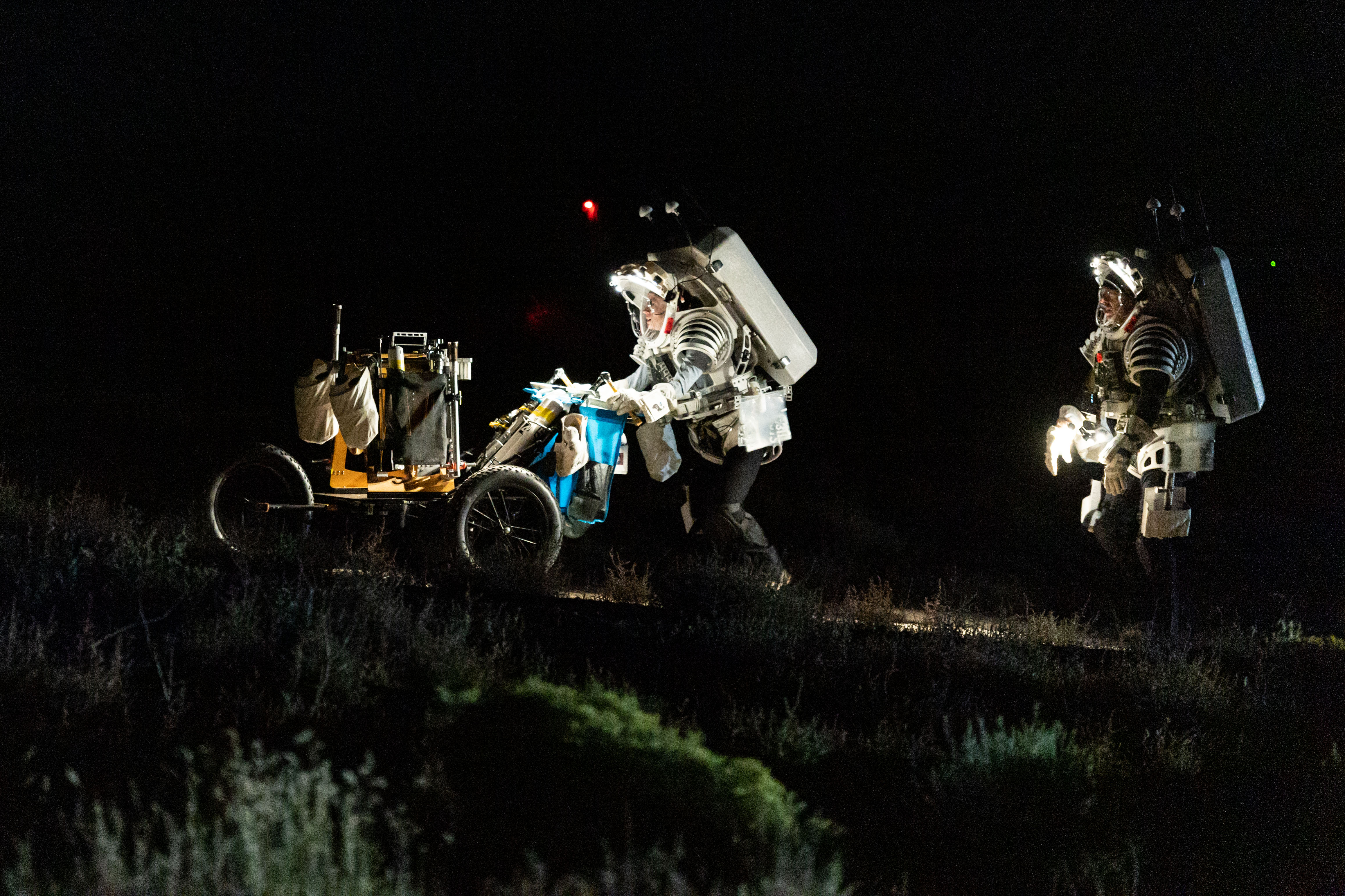 NASA astronauts Zena Cardman (left) and Drew Feustel (right) traverse through the Arizona desert during a simulated moonwalk.