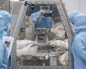 The OSIRIS-REx curation team is pictured removing the TAGSAM head from the capture ring in the avionics deck. Credits: NASA/James Blair