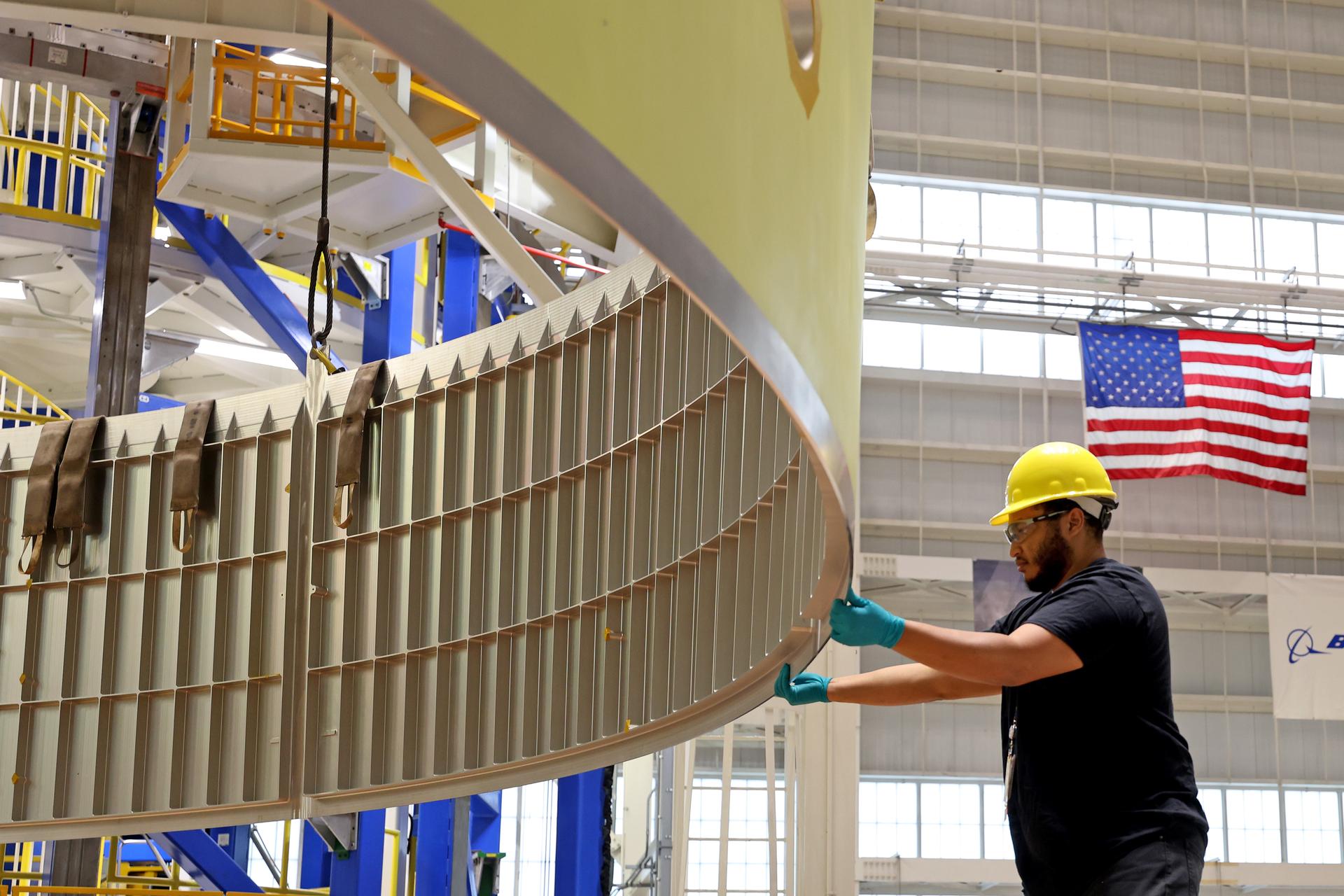 A worker at Michoud Assembly Facility works on the EUS with an American Flag in the background.
