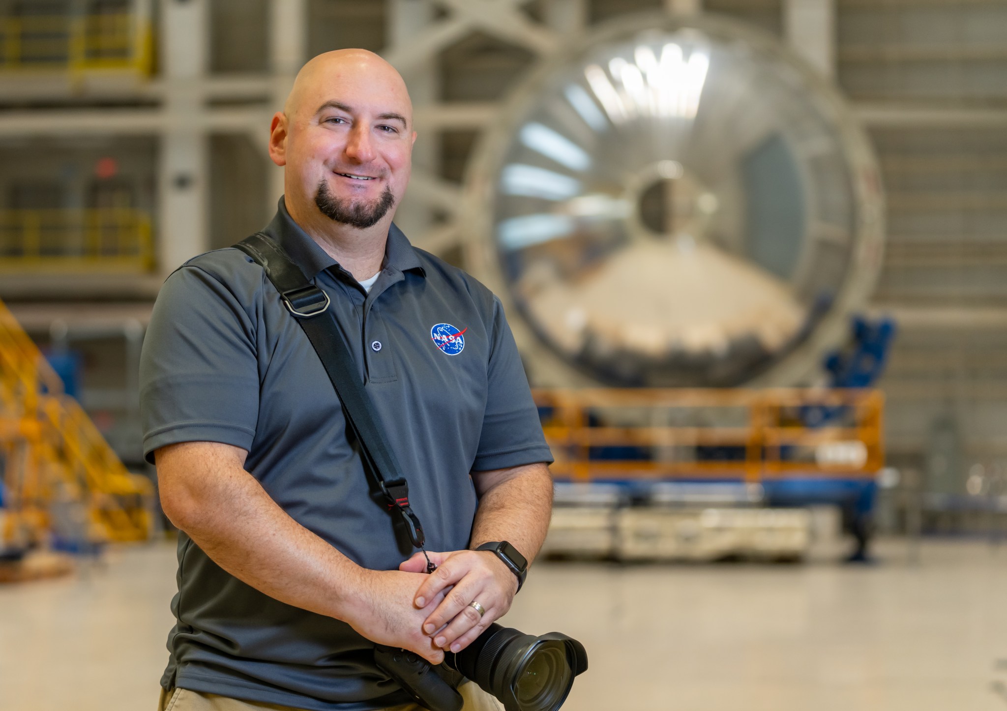 Eric Bordelon, a multimedia specialist at Michoud Assembly Facility, stands in front of a weld confidence article that forms part of the liquid oxygen tank for the SLS (Space Launch System) rocket’s exploration upper stage.