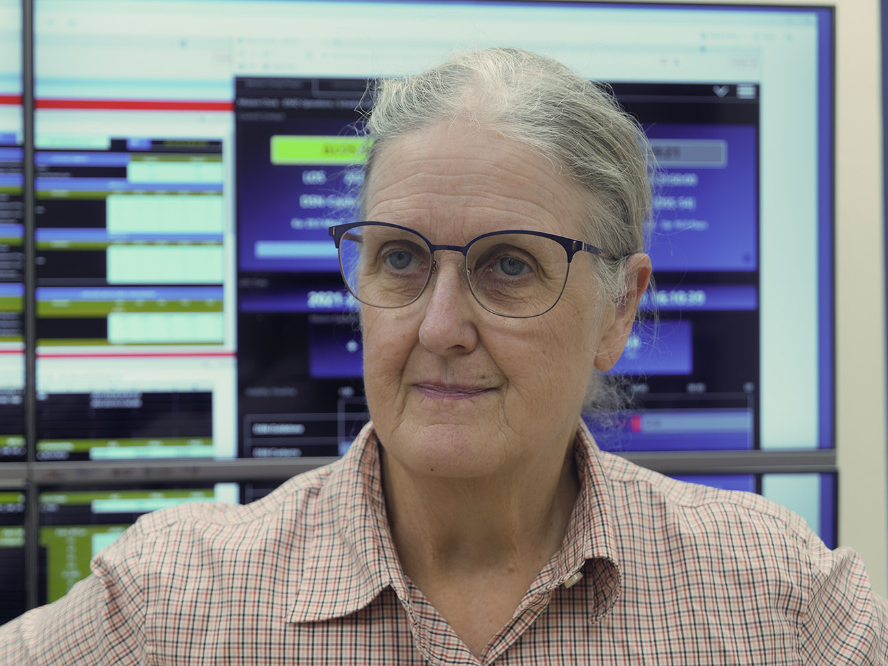 Headshot of Marcia Rieke with a background of blurred monitors of scientific data