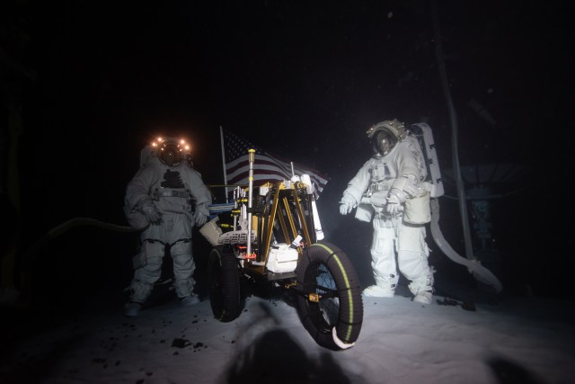 NASA spacesuit engineers Scott Wray (left) and Christine Flaspohler (right) standing next to a tool cart during a simulated moonwalk underwater at NASA Johnson Space Center's Neutral Buoyancy Laboratory.