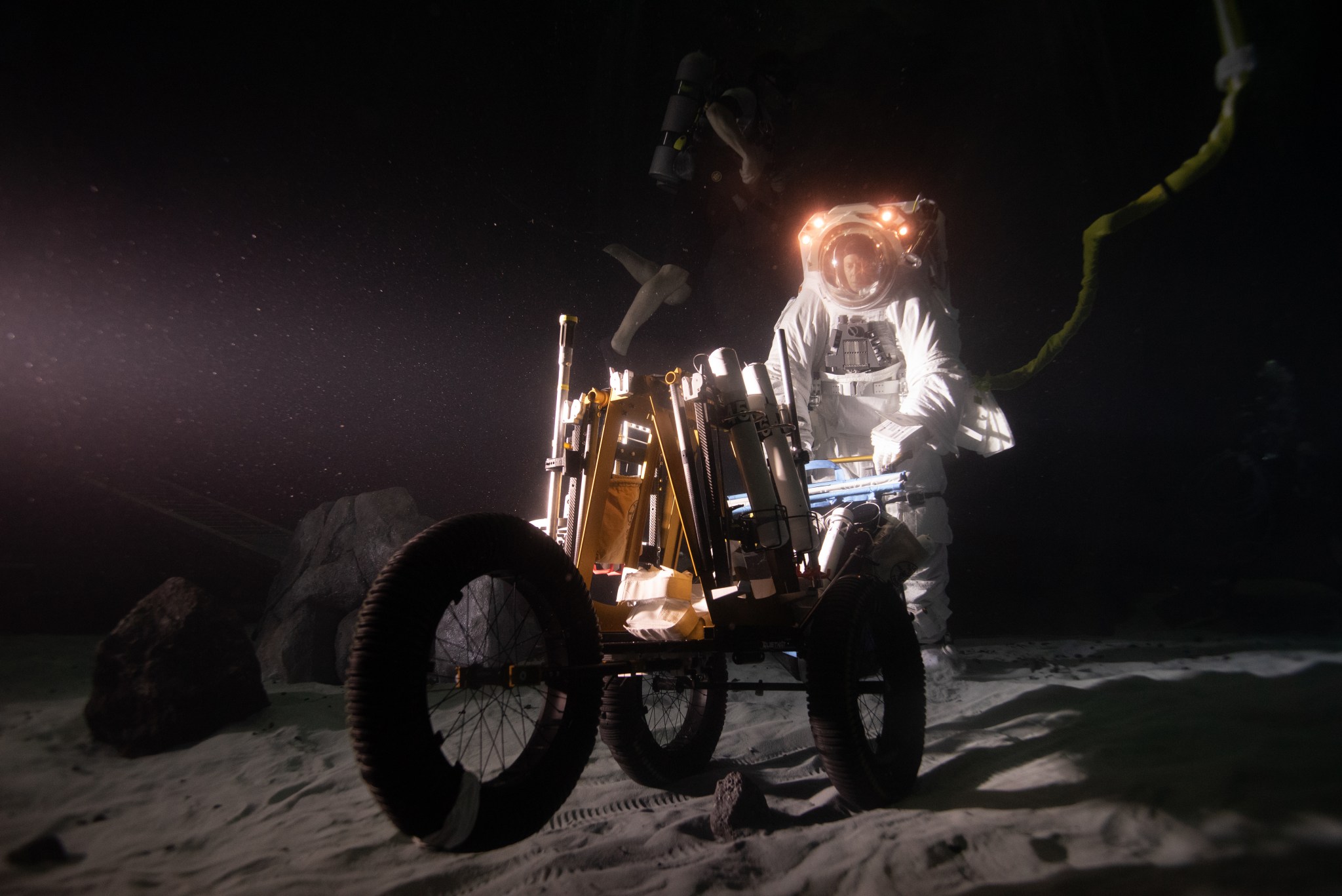 NASA spacesuit engineer Scott Wray pushing a tool cart during a simulated moonwalk underwater at NASA Johnson Space Center's Neutral Buoyancy Laboratory.
