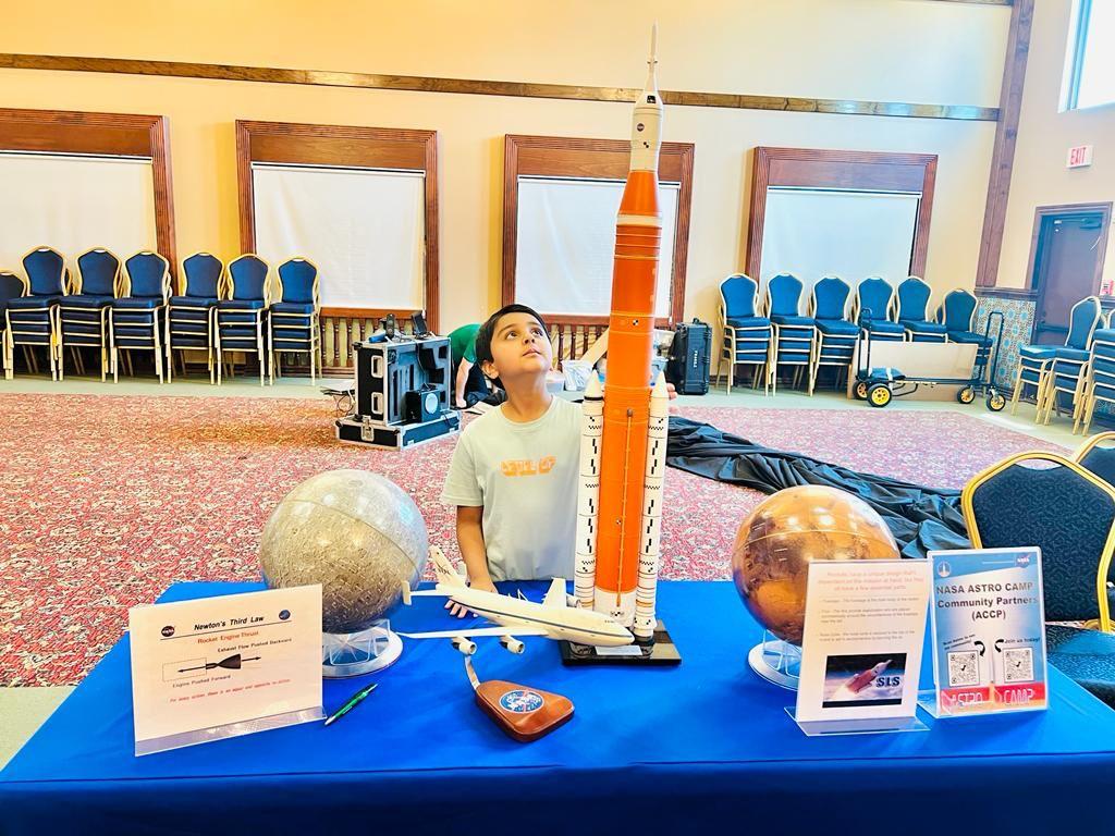 A young male child looking at a model of NASA's SLS rocket