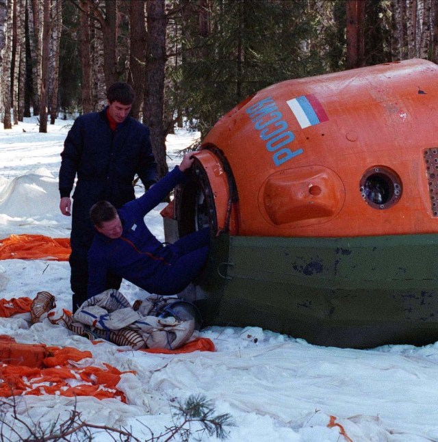Astronaut Bill Shepherd, right, commander of the first crew that will live aboard the International Space Station, exits a mock Soyuz spacecraft while Cosmonaut Sergei Krikalev, left, flight engineer for the first crew, looks on. The crew, which also includes Cosmonaut Yuri Gidzenko as Soyuz Commander, is participating in Soyuz winter survival training in March 1998 near Star City, Russia.