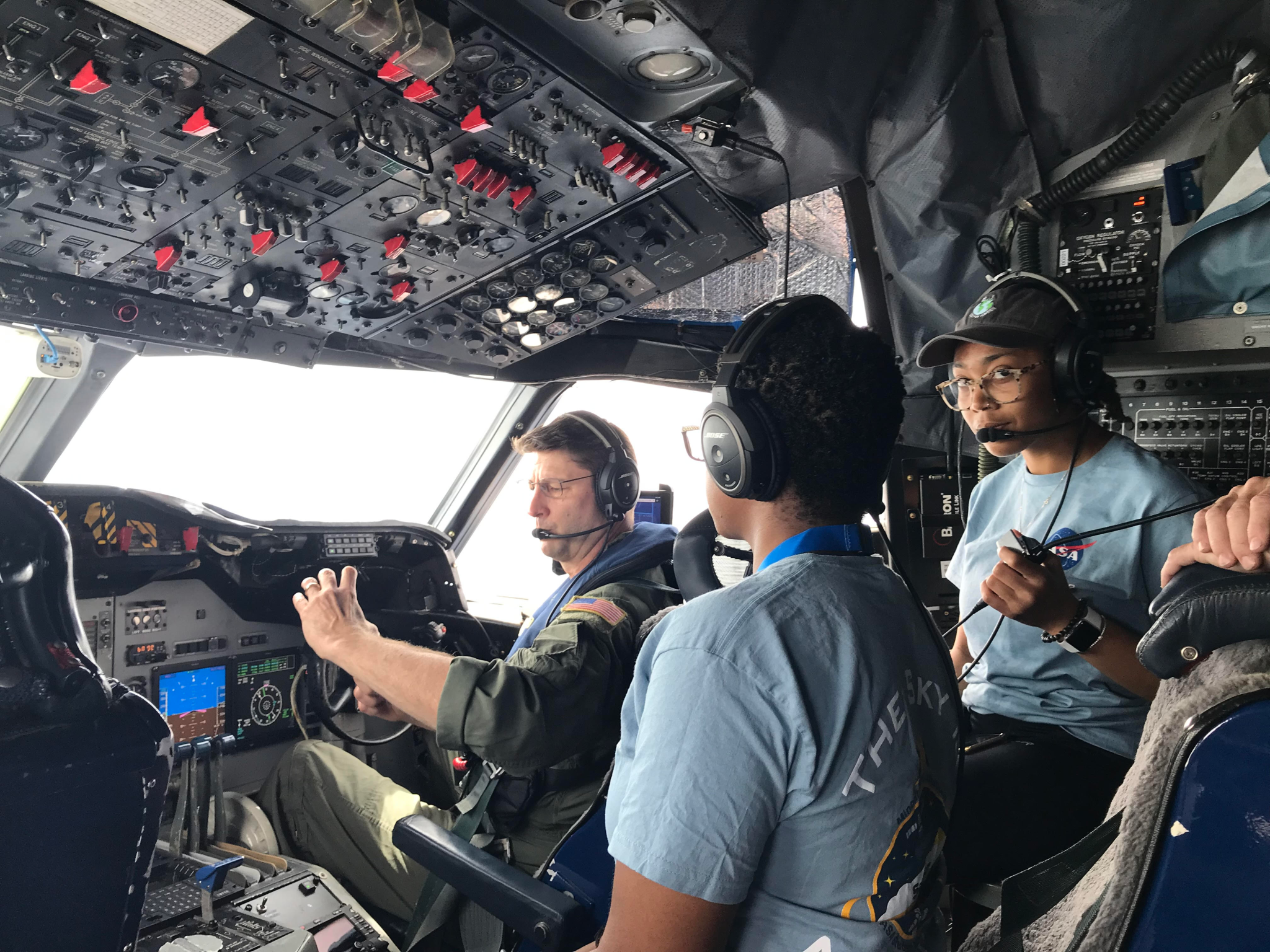 Students of the 2022 SaSa class stand in a cockpit, learning from a NASA airman as part of a training module.