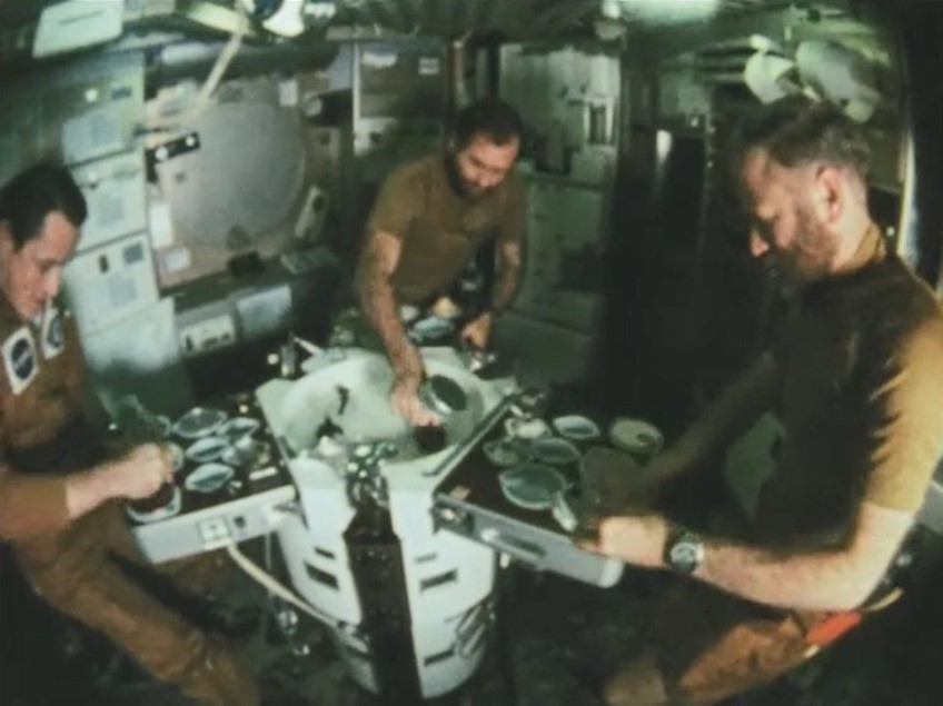 Photo of Edward G. Gibson, left, William R. Pogue, and Gerald P. Carr prepare a meal in the Skylab wardroom
