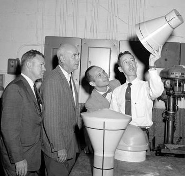 A technician, right, demonstrates a model of a Mercury spacecraft to STG leaders Charles J. Donlan, left, Robert R. Gilruth, and Maxime “Max” A. Faget