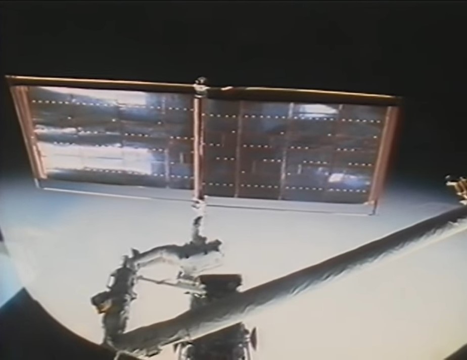 Astronaut Kathryn C. Thornton, on the end of the Remote Manipulator System, releases Hubble’s old solar array that failed to retract properly