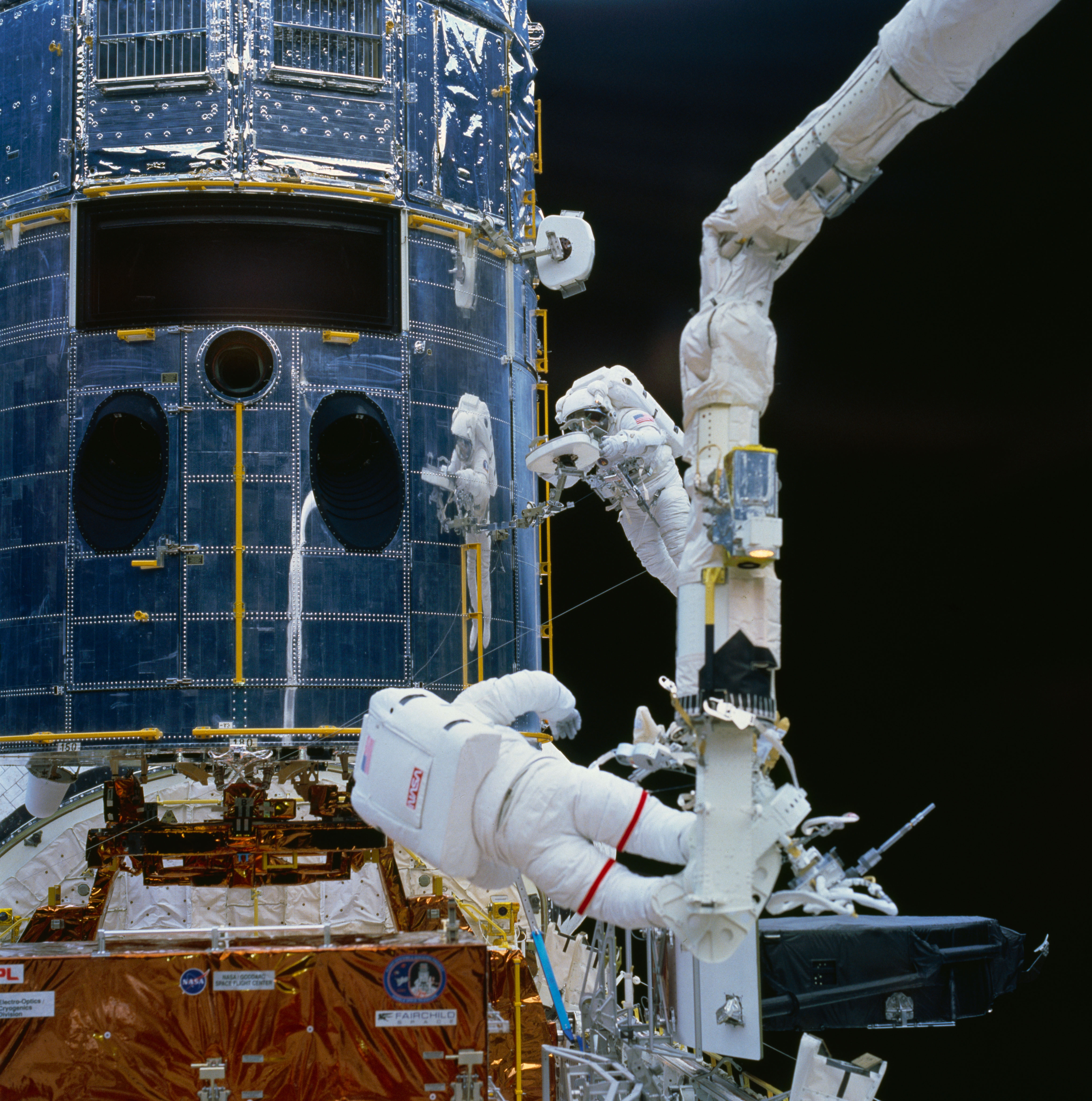 Astronauts Jeffrey A. Hoffman, left, and F. Story Musgrave have removed the old Wide Field Planetary Camera (WFPC) from Hubble, the black rectangle at upper left shows its former location