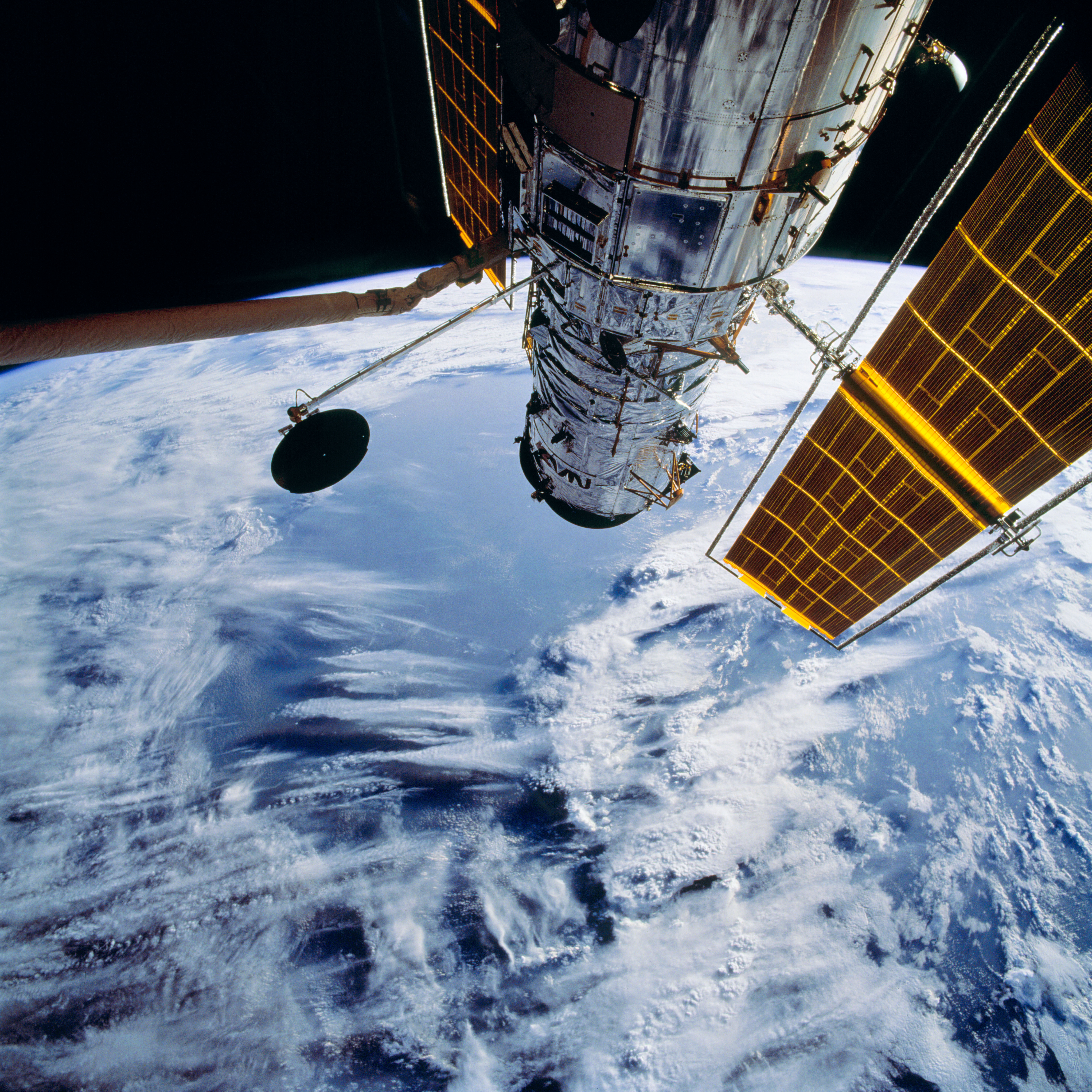 European Space Agency astronaut Claude Nicollier grapples the Hubble Space Telescope, with its high-gain antenna deployed, just prior to release