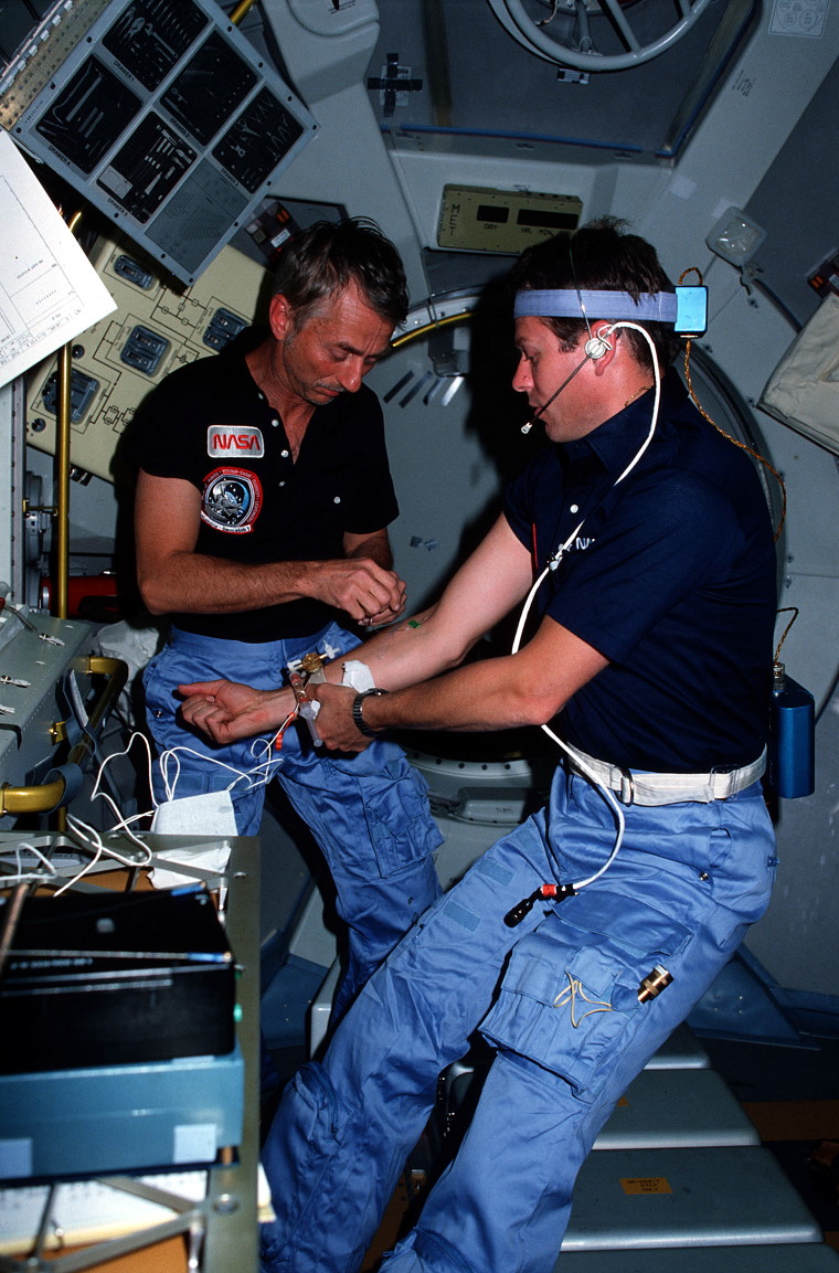 Garriott preparing to draw a blood sample from Lichtenberg for one of the life sciences experiments