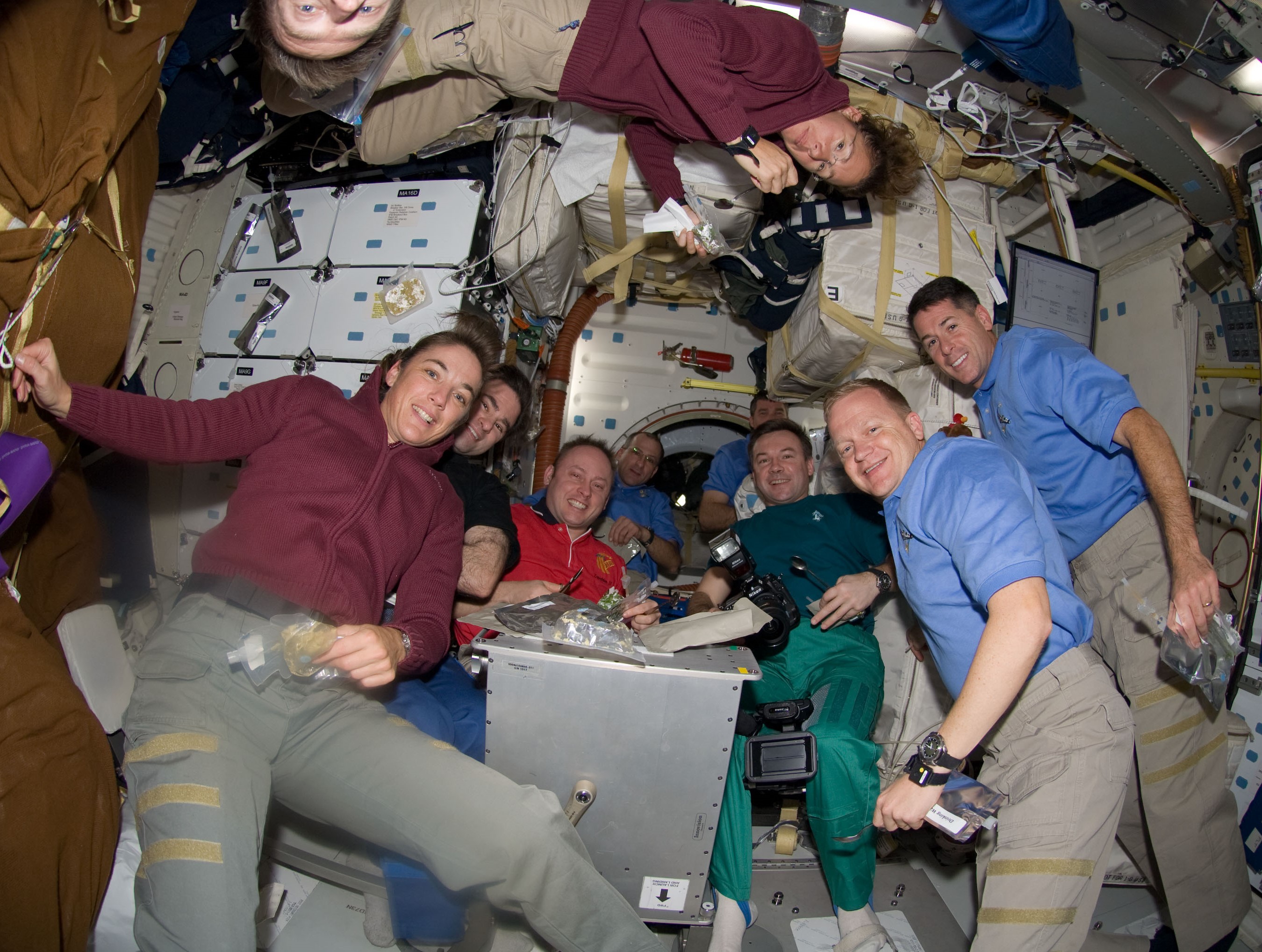 The crews of Expedition 18 and STS-126 share a meal in the space shuttle middeck