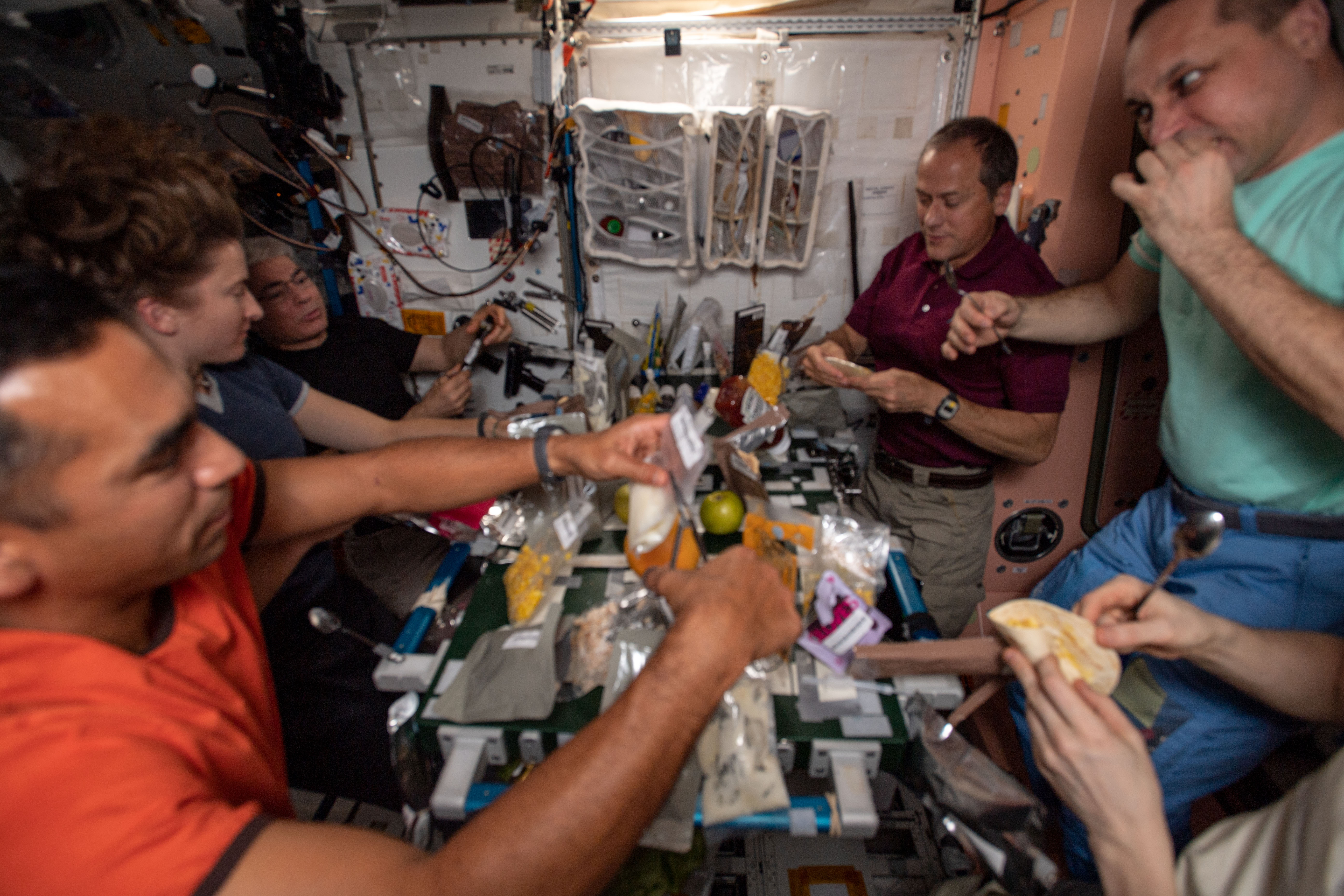 Expedition 66 crew members NASA astronauts Raja J. Chari, left, Kayla S. Barron, Mark T. Vande Hei, Thomas H. Marshburn, Russian cosmonauts Anton N. Shkaplerov and Pyotr V. Dubrov (partially visible), and European Space Agency astronaut Matthias J. Maurer (taking the photo) enjoy the Thanksgiving feast