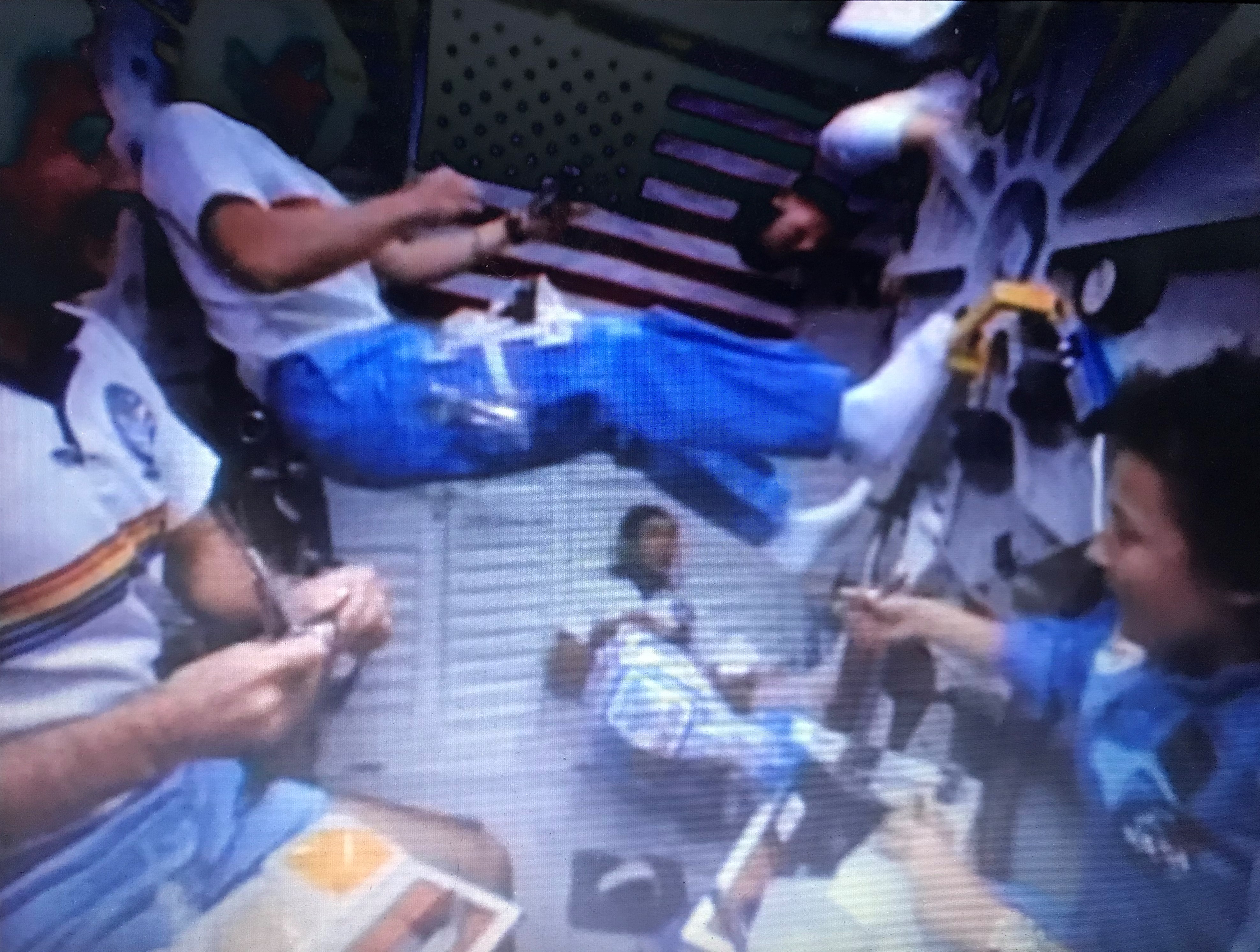 Image of the STS-61B crew enjoying their Thanksgiving dinner while floating in Atlantis’ middeck