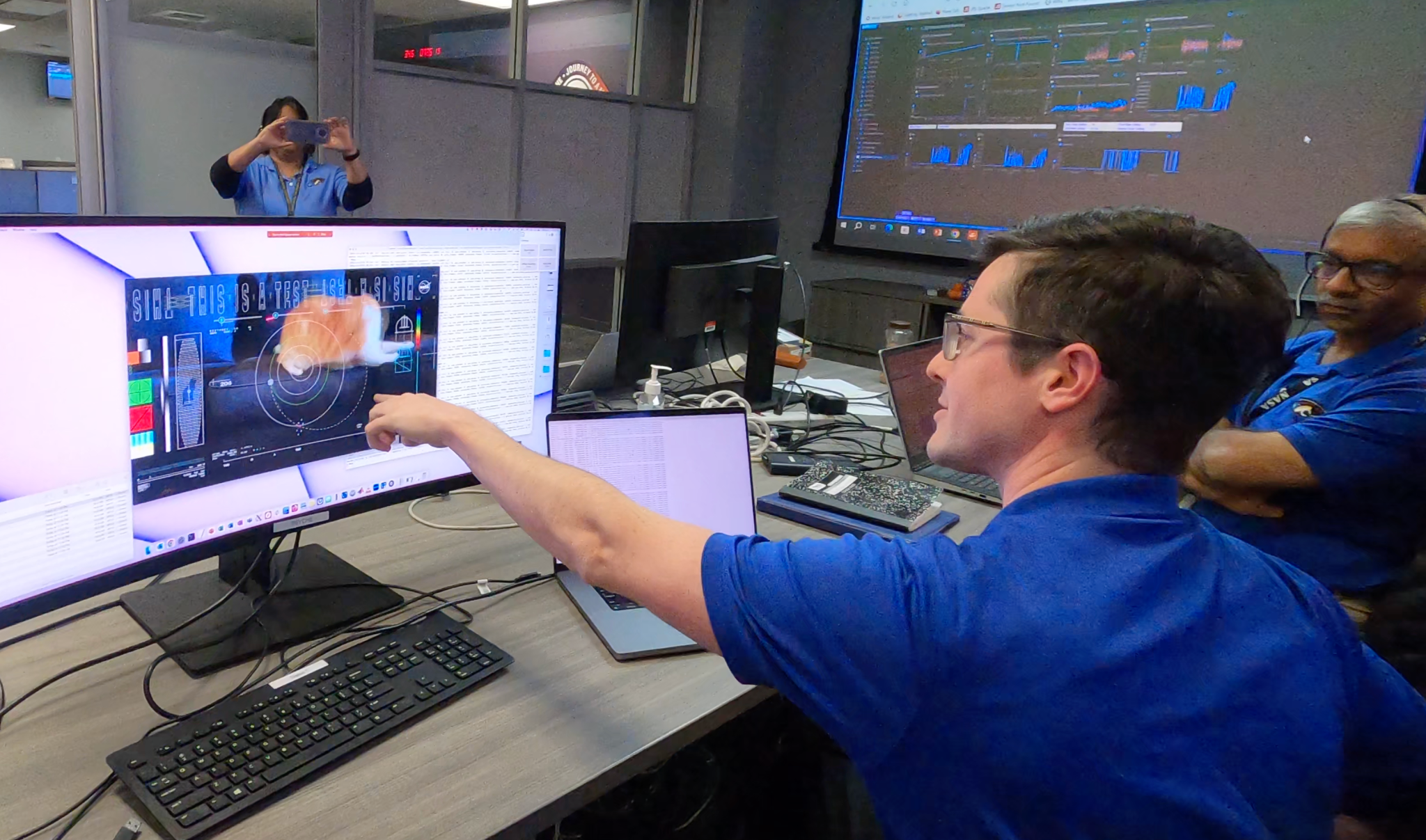 Members of the DSOC team react to the first high-definition streaming video to be sent via laser from deep space on Dec. 11 at NASA’s Jet Propulsion Laboratory. Sent by the DSOC transceiver aboard the Psyche spacecraft, nearly 19 million miles from Earth, the video features a cat named Taters.