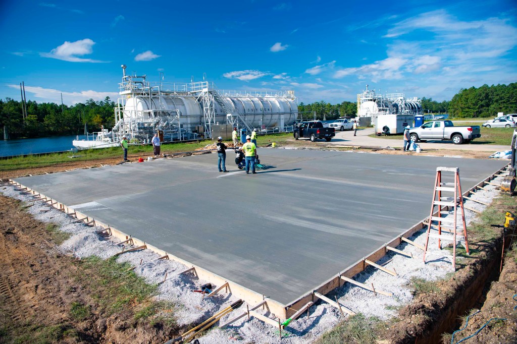 construction workers smooth concrete foundation of new test pad