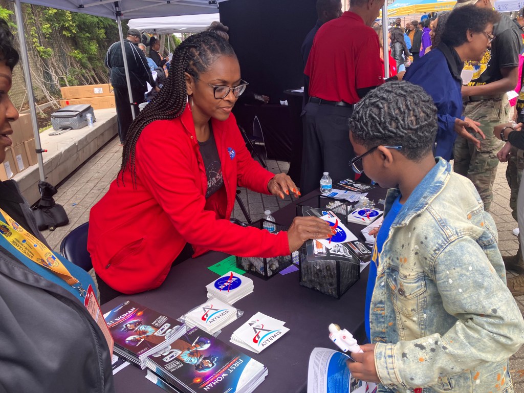 Dawn Davis, chief of Technology Transfer at NASA Stennis, gives a NASA sticker to a young boy