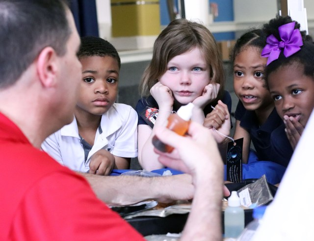 Elementary students gather closely to learn facts about living in space