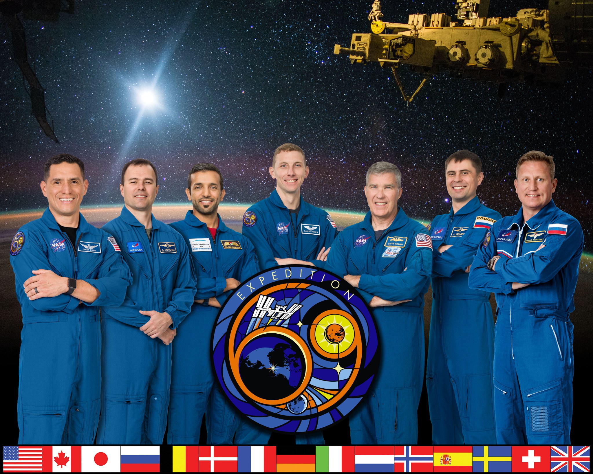 The Crew stand in a line in blue flight suits with the mission patch over their photo.