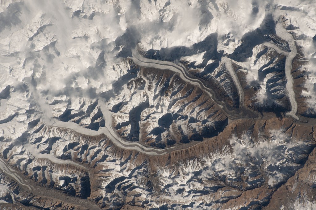 iss070e035652 (Dec. 2, 2023) -- Snow drifts through the Karakoram mountain range as low-hanging clouds blend into the snow-capped summits of mountains as the International Space Station soared 259 miles above Pakistan.
