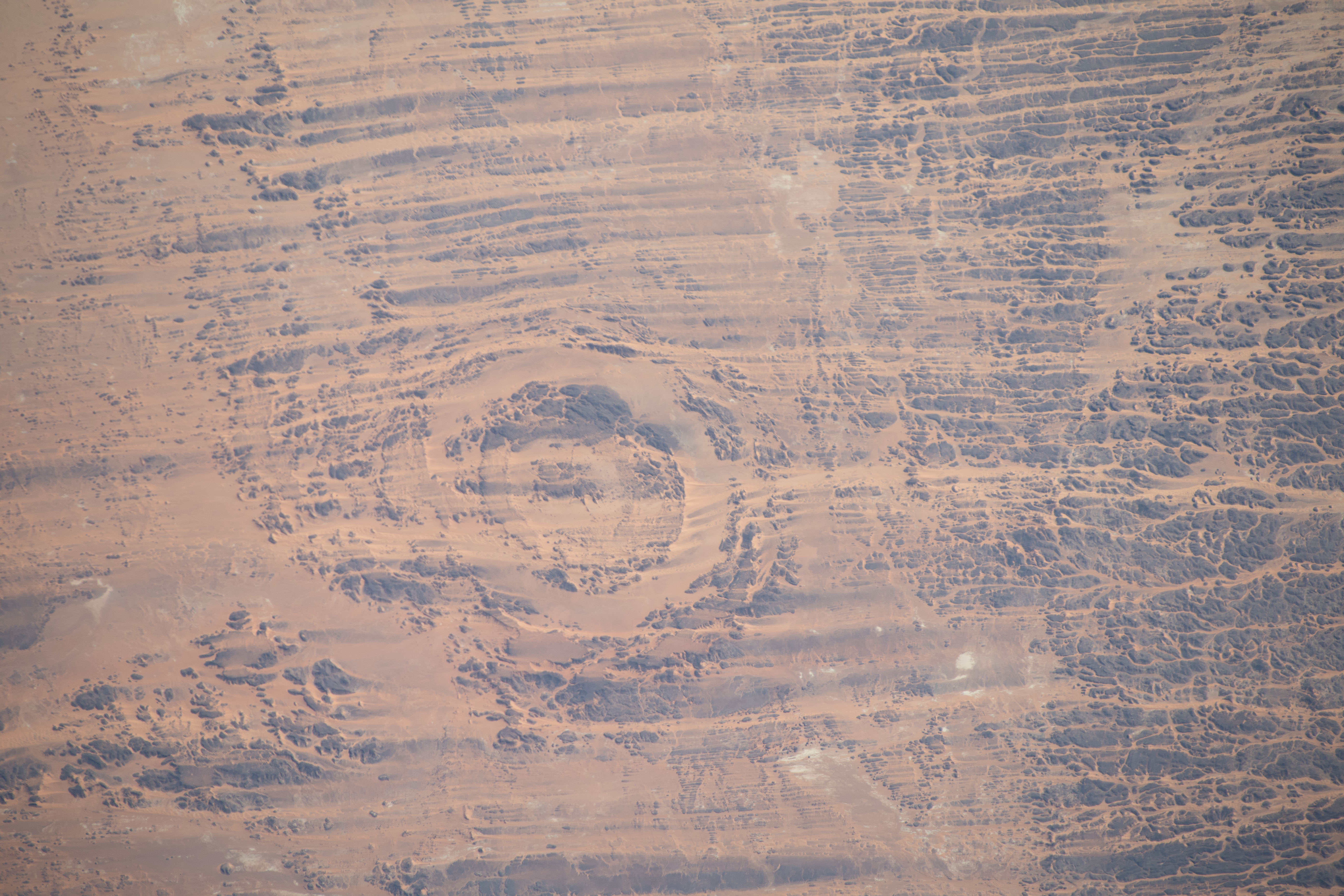 iss070e045218 (Dec. 23, 2023) -- Located in the Sahara Desert, the Aorounga Impact Crater stretches nearly 8 miles (~12.6km) in diameter. The crater is thought to be approximately 325-370 million years old, with outer and inner rings that rise about 330 feet (100 meters) above the surrounding terrain. As the International Space Station soared 258 miles above north-central Chad, this image was taken.