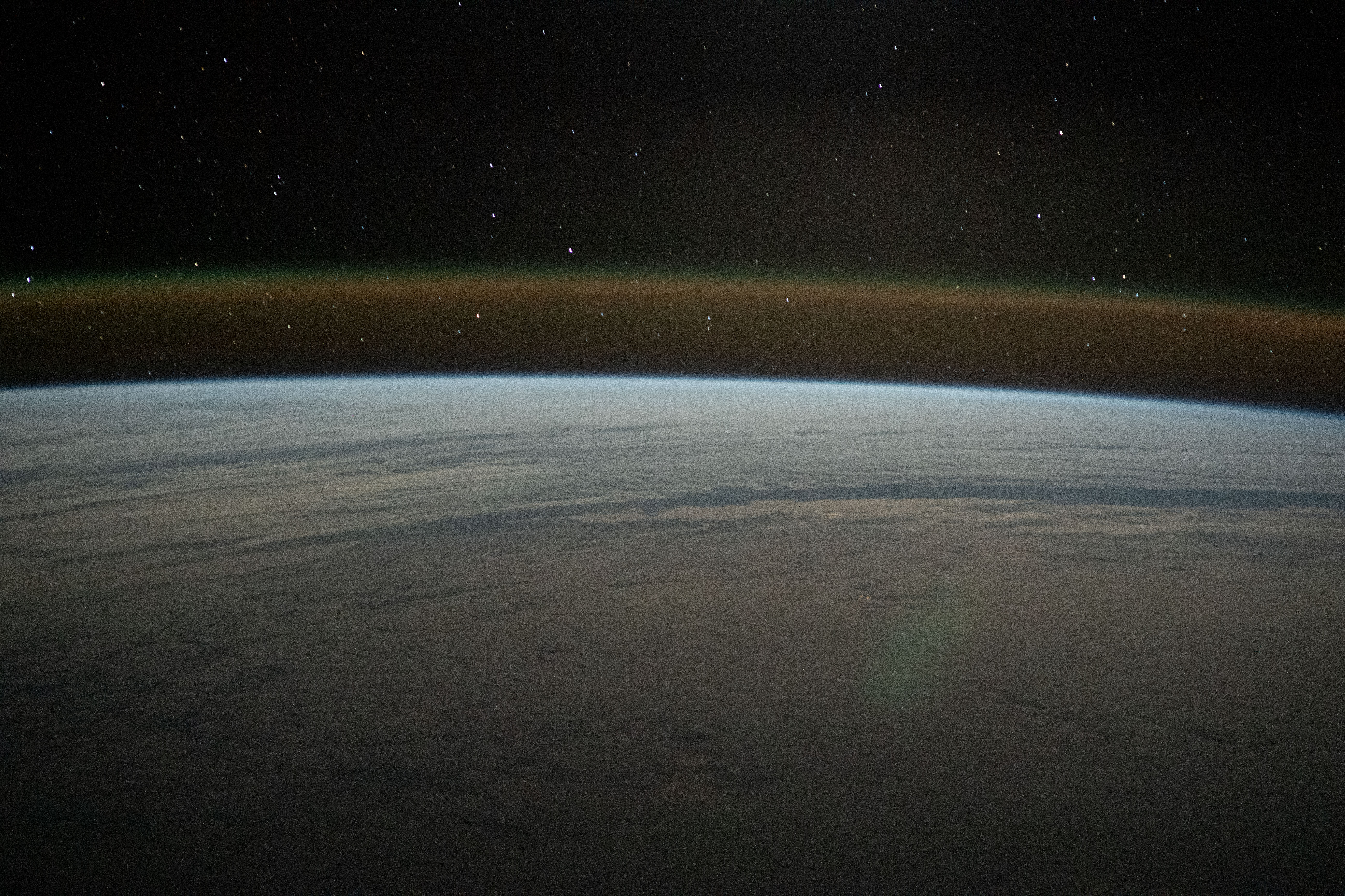 This tranquil orbital pass above a cloud-covered Atlantic Ocean reveals Earth's atmospheric glow beneath a starry sky as the International Space Station soared 271 miles above.