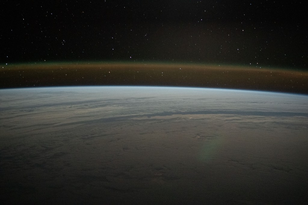 This tranquil orbital pass above a cloud-covered Atlantic Ocean reveals Earth's atmospheric glow beneath a starry sky as the International Space Station soared 271 miles above.