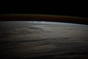 A cloudy, south Indian Ocean between Africa and Antarctica, with lightning storms near the horizon beneath the atmospheric glow, is pictured from the International Space Station as it orbited 271 miles above