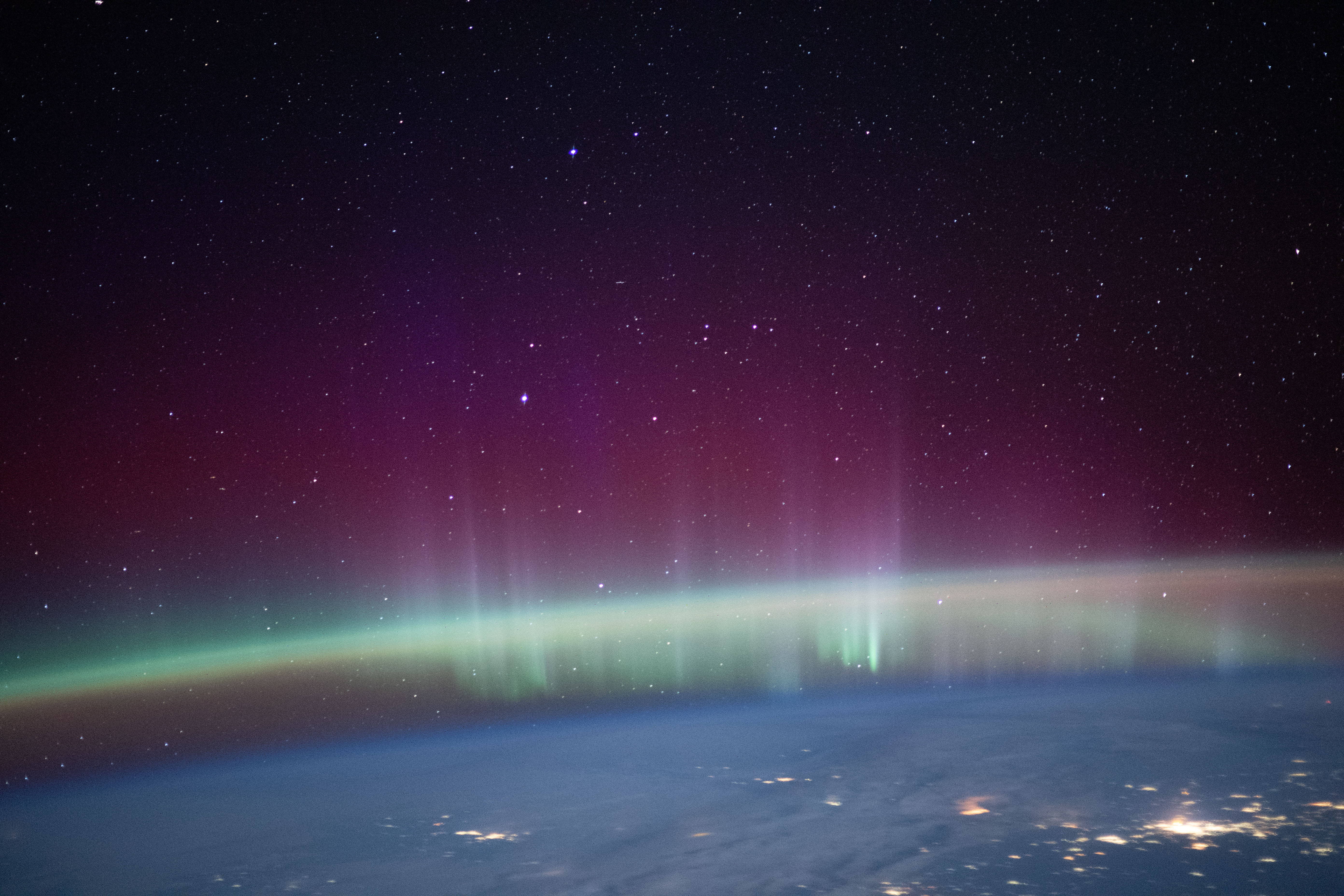 An aurora intersects Earth's airglow beneath a starry sky in this photograph from the International Space Station as it orbited 261 miles above western Kazakhstan near the Caspian Sea.