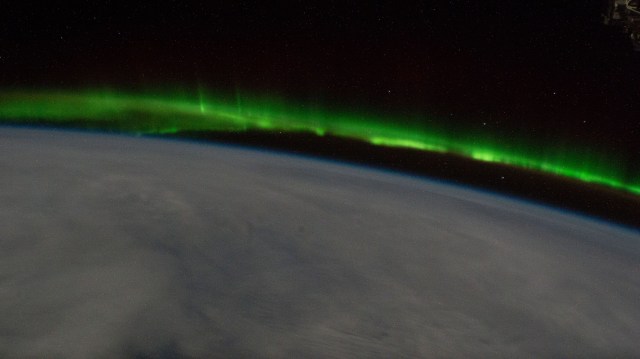 An aurora streams above a cloudy Earth as the International Space Station orbited 268 miles above the south Pacific.