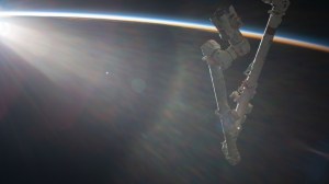 An orbital sunrise begins illuminating Earth's atmosphere with the International Space Station's Canadarm2 robotic arm extending from the orbital lab as it soared 260 miles above the Pacific Ocean.