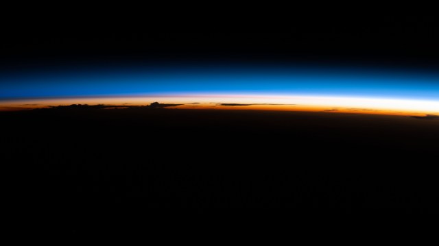 An orbital sunrise illuminate's Earth's atmosphere silhouetting clouds as the International Space Station soared 264 miles above the Paraguay-Brazil border in South America.