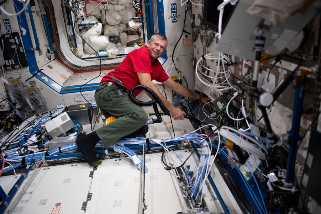 ESA (European Space Agency) and Expedition 69 Flight Engineer Andreas Mogensen uses a vacuum cleaner to clean fans, filters, and ventilation systems aboard the International Space Station.