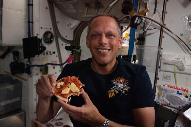 NASA astronaut and Expedition 67 Flight Engineer Bob Hines enjoys a personal size pizza during dinner time aboard the International Space Station.