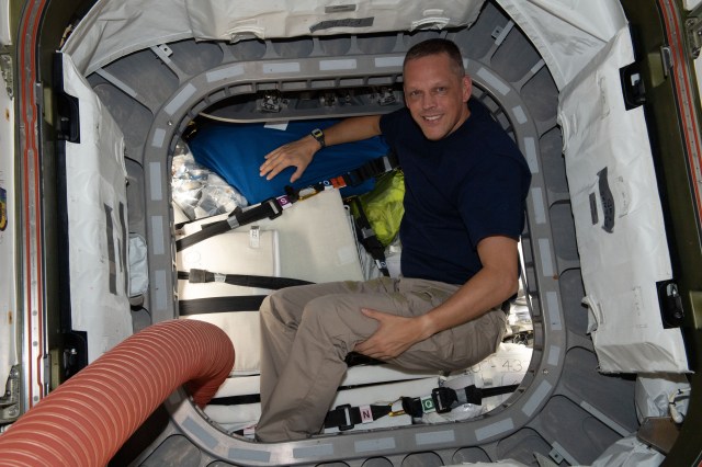 NASA astronaut and Expedition 67 Flight Engineer Bob Hines is pictured inside the vestibule between the Unity module and the Cygnus space freighter finalizing cargo operations the day before the vehicle's departure from the International Space Station.