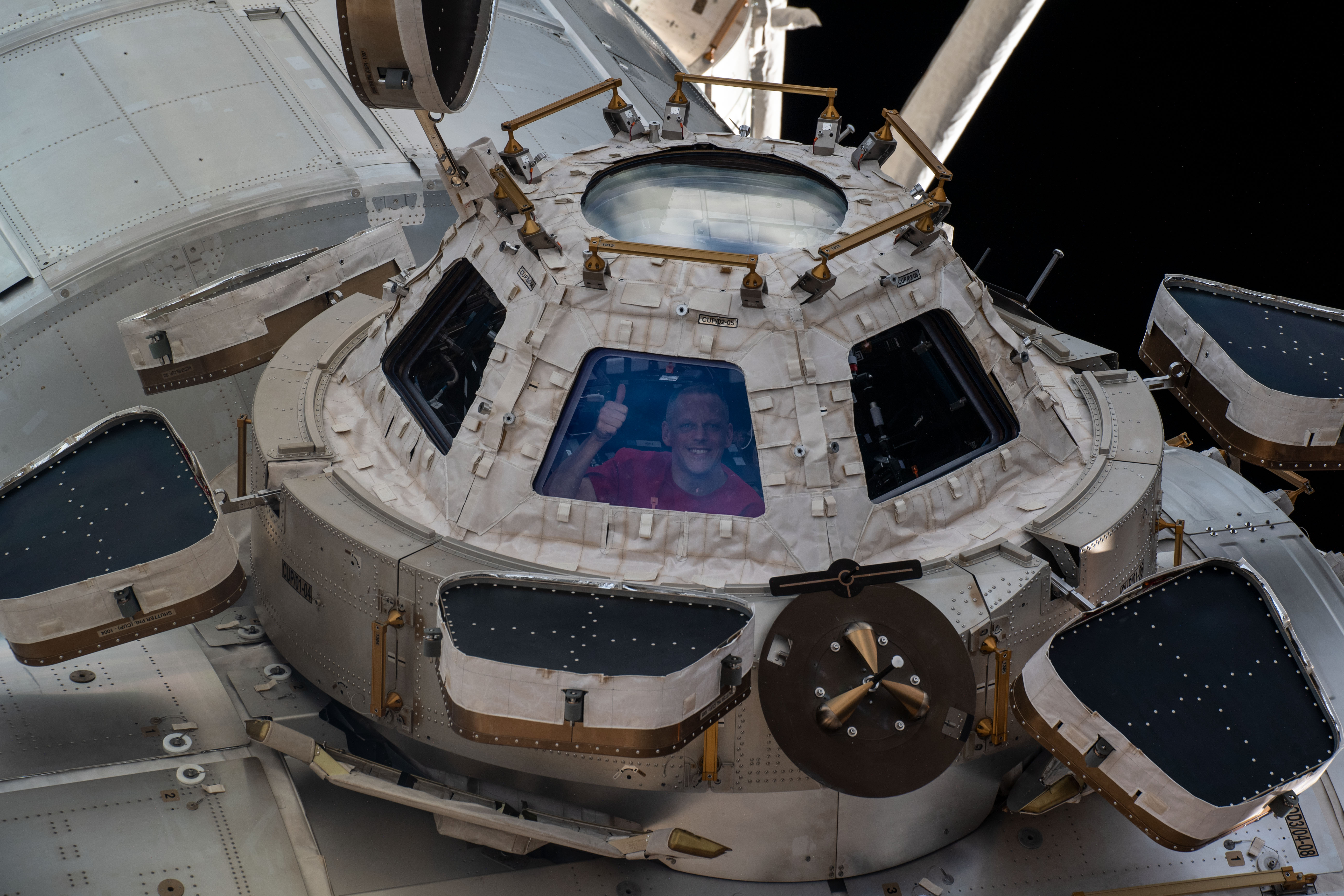 NASA astronaut and Expedition 67 Flight Engineer Bob Hines is pictured looking out from a window on the cupola, the International Space Station's "...