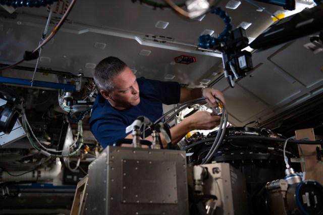 NASA astronaut and Expedition 67 Flight Engineer Bob Hines replaces components inside the Combustion Integrated Rack, a research device that enables safe investigations into how flames, fiuel, and soot behave in microgravity.