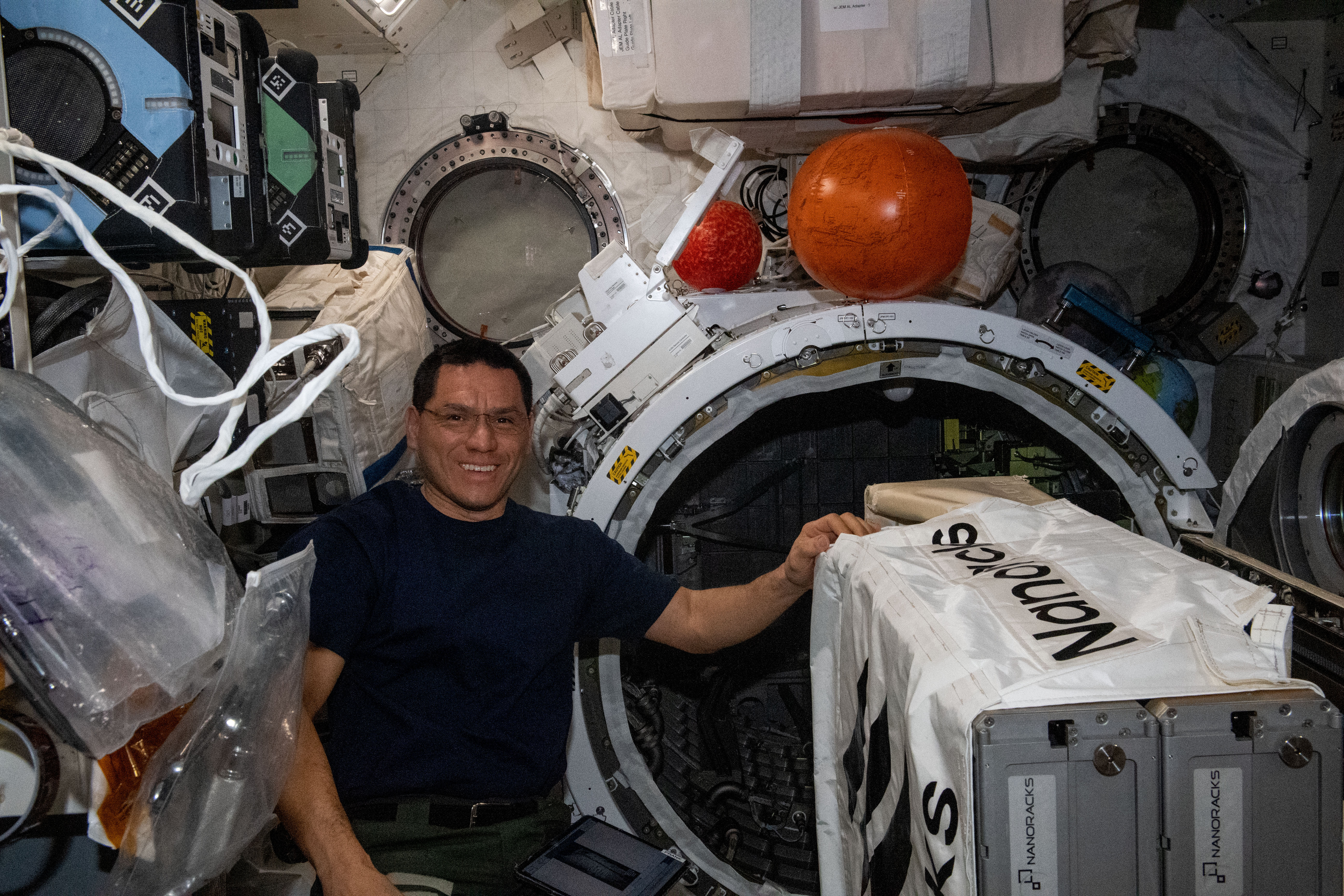 NASA astronaut and Expedition 69 Flight Engineer Frank Rubio works to install the NanoRacks CubeSat Deployer inside the Kibo laboratory module's airlock. After the airlock is depressurized, the Japanese robotic arm grapples the deployer and places it outside in the vacuum of microgravity pointing it away from the International Space Station. CubeSats from private, governmental, and academic organizations are then deployed into Earth orbit for a variety of research objectives.