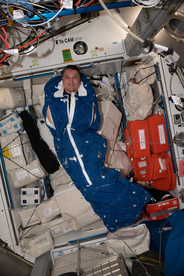 NASA astronaut and Expedition 67 Flight Engineer Kjell Lindgren poses for a portrait inside a crew sleeping bag aboard the International Space Station.