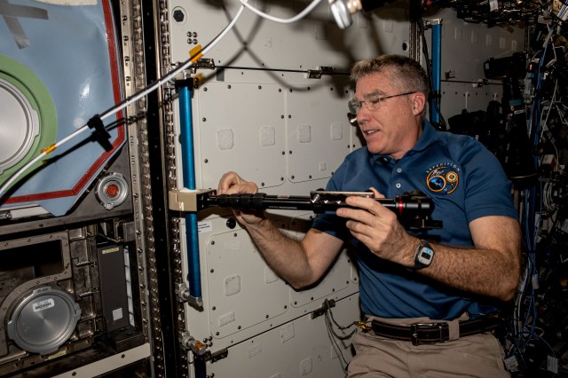 NASA astronaut and Expedition 69 Flight Engineer Stephen Bowen installs student-made hardware next to the Destiny laboratory module's Microgravity Science Glovebox to test a platform that improves the stability of cameras used to track targets on the ground or take images and video inside the International Space Station.
