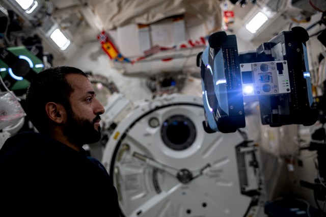 UAE (United Arab Emirates) astronaut and Expedition 69 Flight Engineer Sultan Alneyadi observes a free-flying Astrobee robotic assistant during the testing of its operations for an upcoming student competition to control the robotic devices.