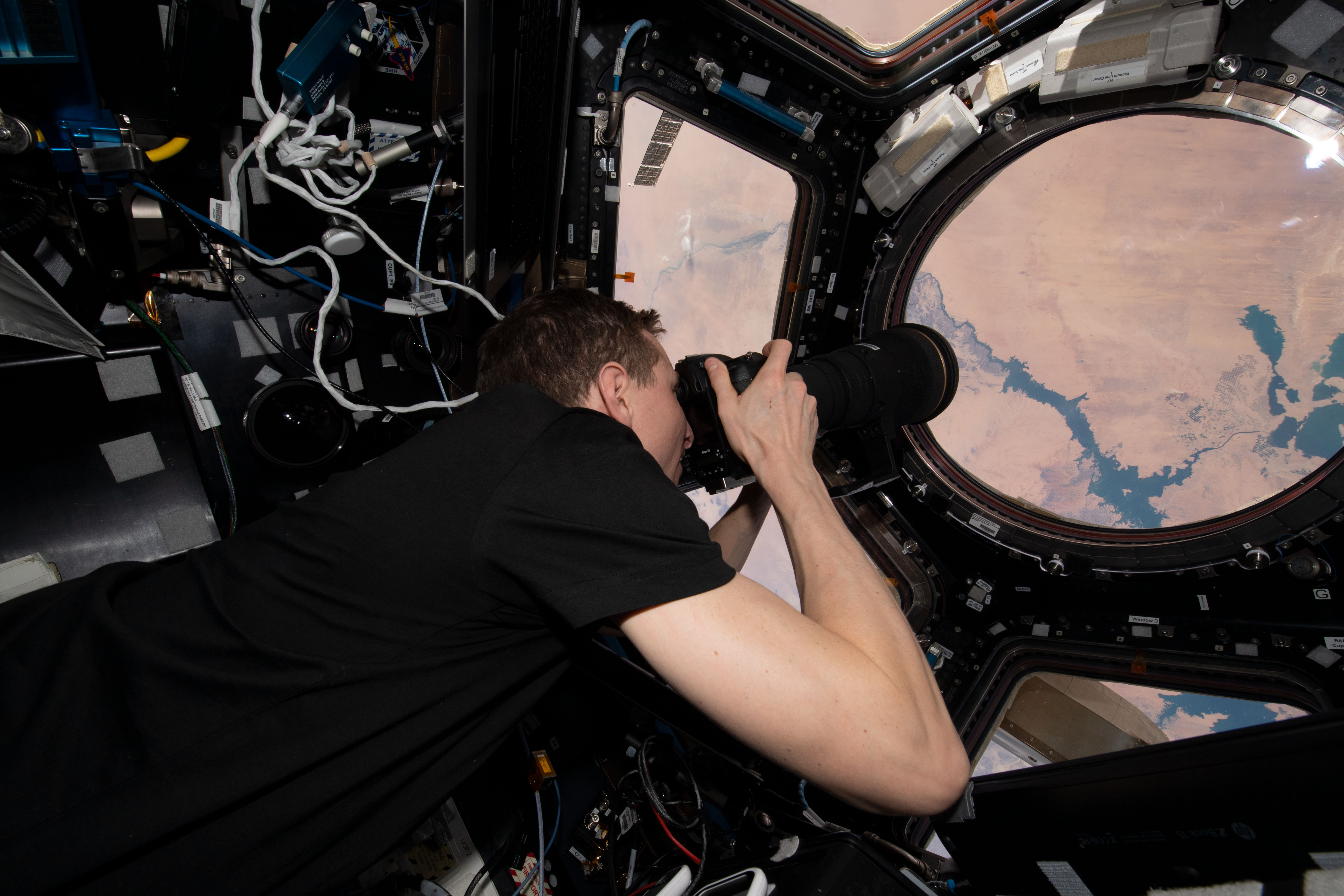 NASA astronaut and Expedition 69 Flight Engineer Woody Hoburg is pictured inside the seven window cupola photographing Lake Nasser in Egypt as the International Space Station orbited 257 miles above.